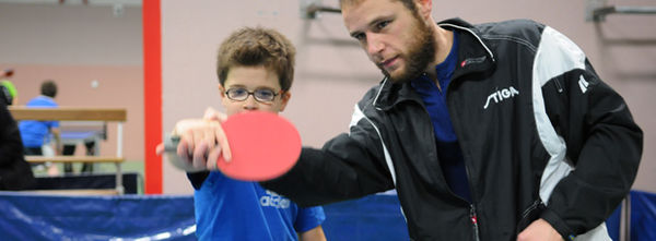 Photo d'un enfant en train d'apprendre à jouer au tennis de table